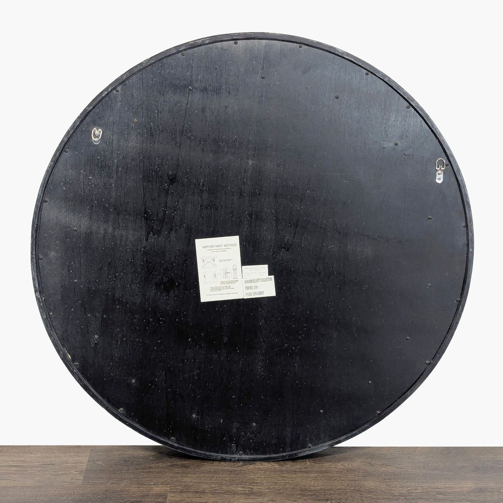 Back view of the Howard Elliott round mirror, showing hanging hardware and manufacturer labels.  