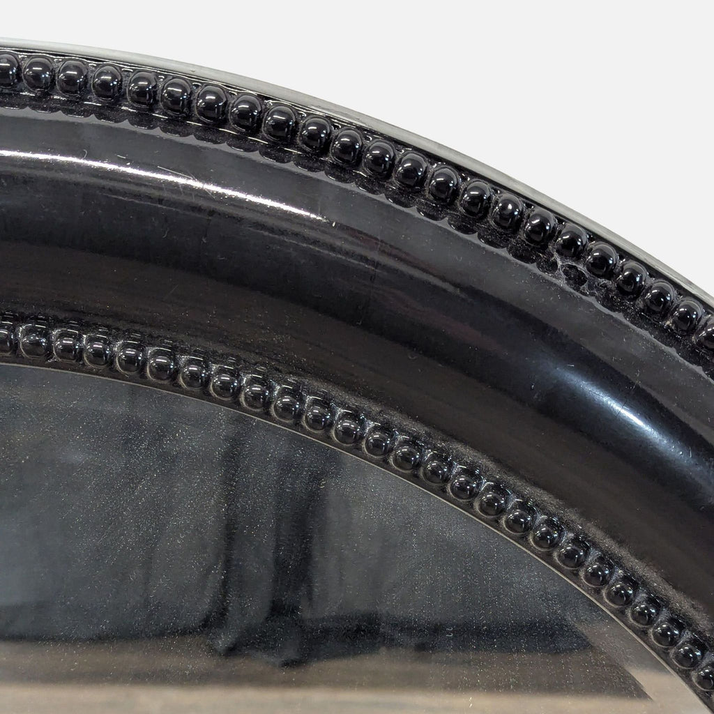 Close-up of the black resin frame on the Howard Elliott mirror, highlighting its beaded detailing.