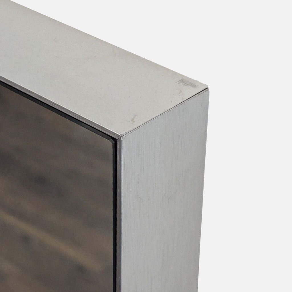 3. Detail of the CB2 mirror's corner, showing the brushed metal frame and seamless edge construction.