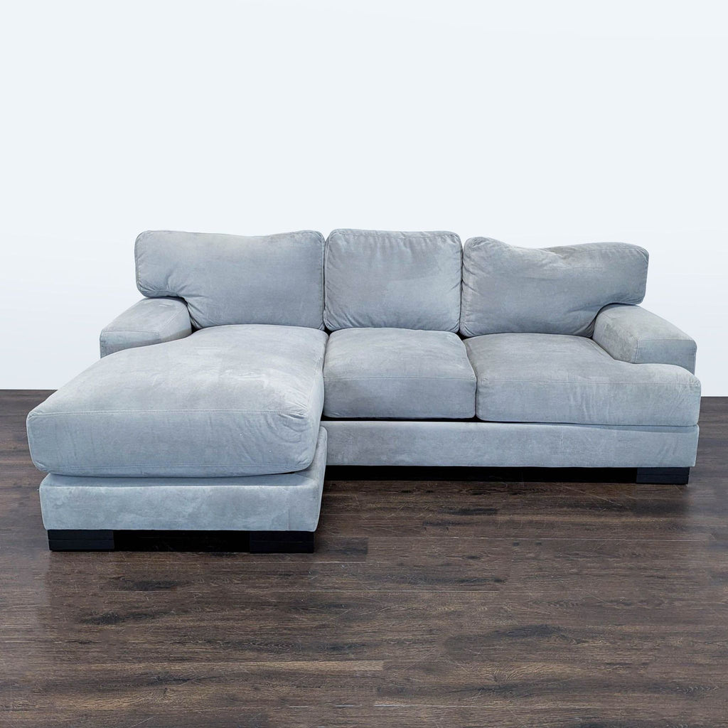 Modern gray Living Spaces sectional sofa with chaise lounge, thick cushions, and wide arms in clean, used condition.  