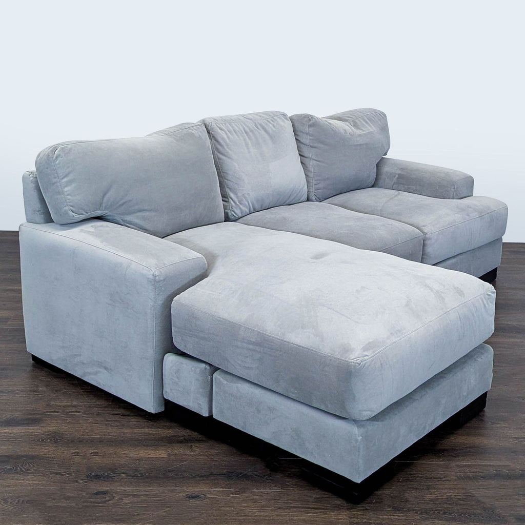 Soft gray sectional sofa by Living Spaces featuring a chaise, spacious seating, and sturdy build, ideal for living rooms.  