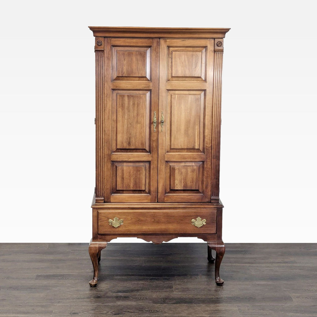1. Queen Anne-style cherry wood armoire with paneled doors, curved legs, and brass hardware by Statton Furniture.