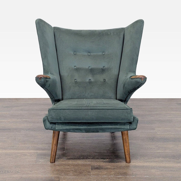 1. Hans Wegner lounge chair in dark green upholstery, high back, winged sides, and wooden legs, viewed from front.
