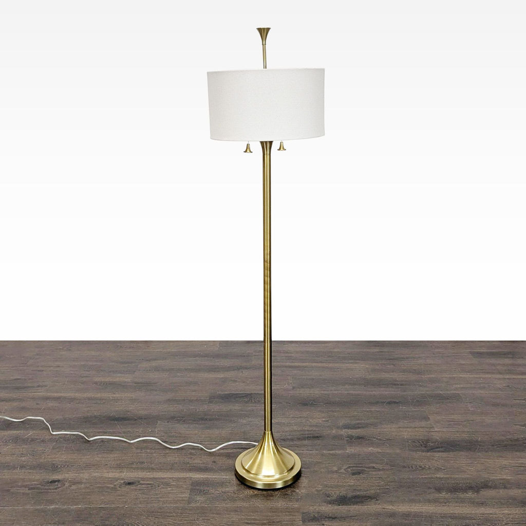 Brass floor lamp with a white drum shade and dual pull chains for adjustable lighting, perfect for home or office.