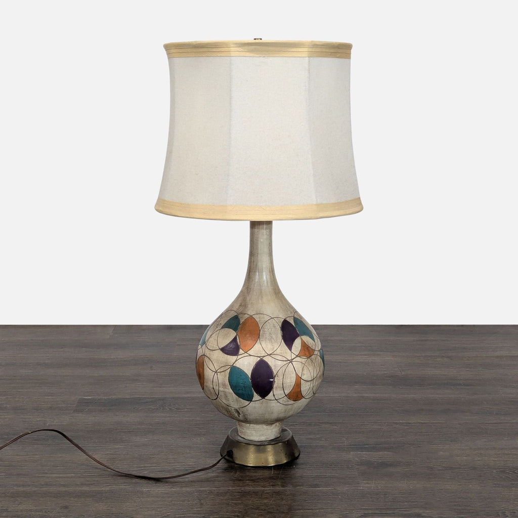 Gourd-shaped table lamp with vibrant geometric ceramic base and cream fabric shade with gold trim.