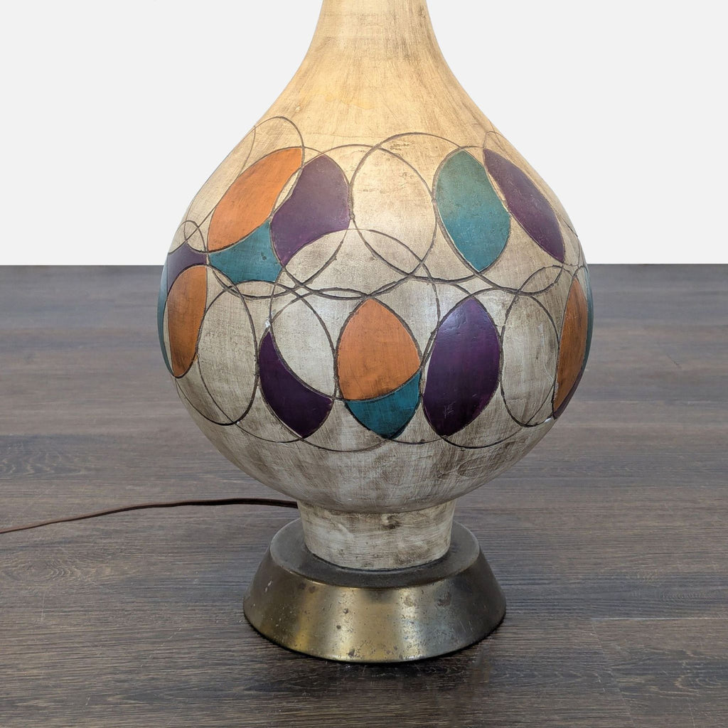 Colorful ceramic table lamp featuring purple, orange, and teal patterns, and a gold-trimmed cream shade.
