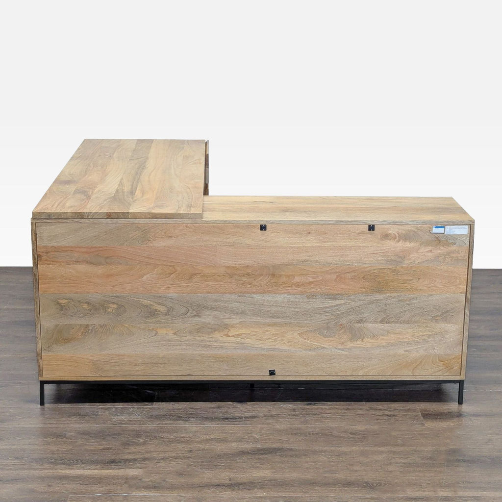 Natural wood L-shaped West Elm desk with drawers and open shelving, ideal for organizing an office.