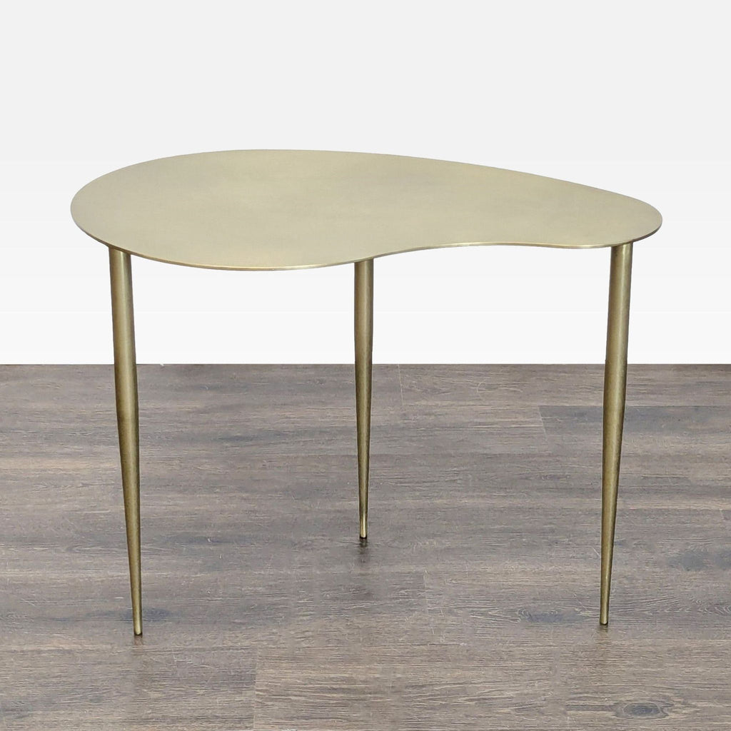 1. Modern side table with a gold kidney-shaped top and three slender legs, standing on wood flooring.