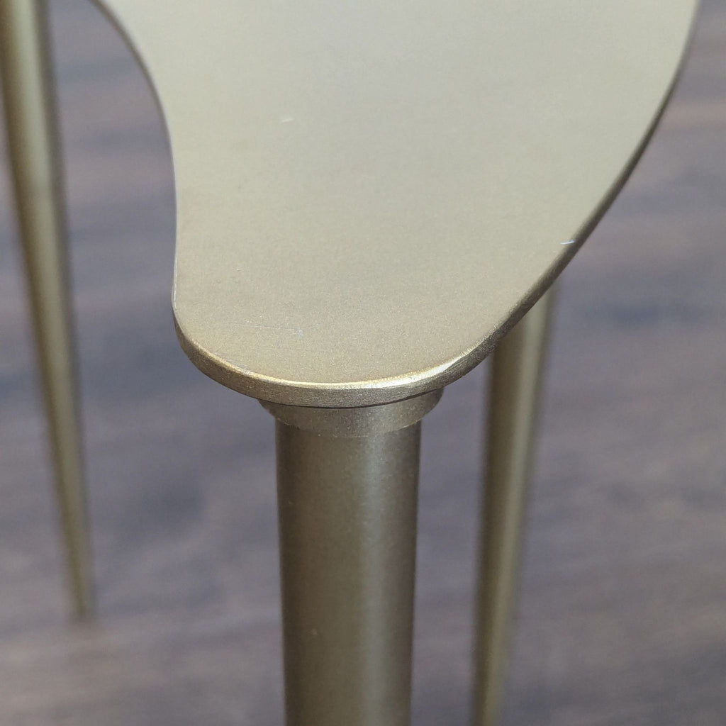 3. Close-up of a gold-finish table corner, highlighting the smooth edge and one tapered metal leg.