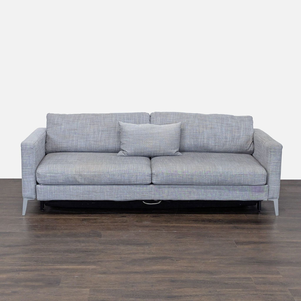 Gray sleeper sofa with a pull-out bed, clean modern design, and includes a matching pillow.