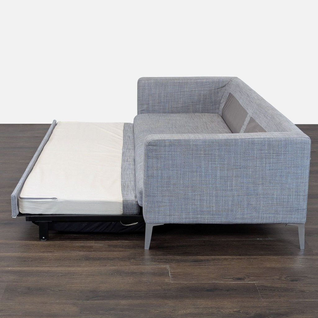 Convertible gray sleeper sofa with matching pillow, ideal for small spaces and overnight guests.