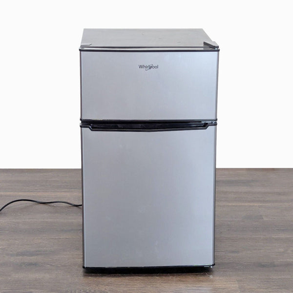 Whirlpool mini refrigerator with sleek silver finish, separate freezer, and compact design for small spaces.