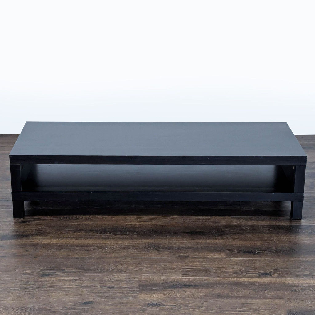 2. Low-profile black IKEA TV stand with a single open shelf, viewed from the front, on a wooden floor.
