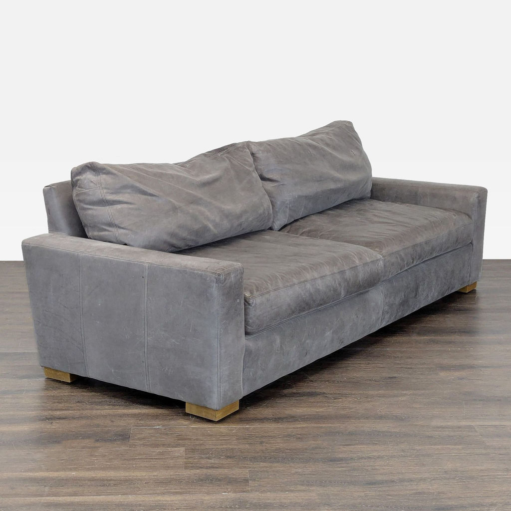Angled view of a Restoration Hardware gray leather 3-seat sofa, showcasing deep seats and sturdy frame design.