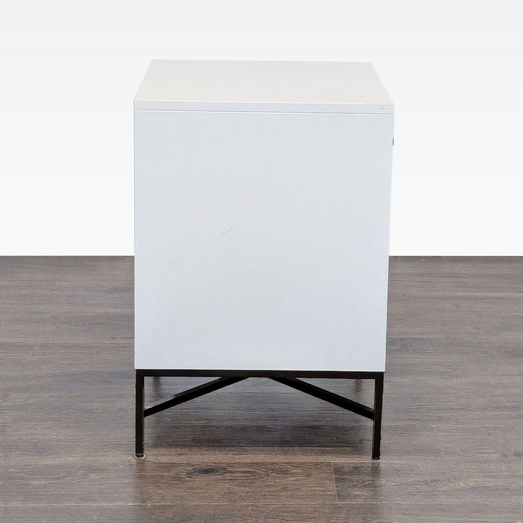 3. Rear view of white West Elm end table with minimalist design, smooth surface, and black metal base.