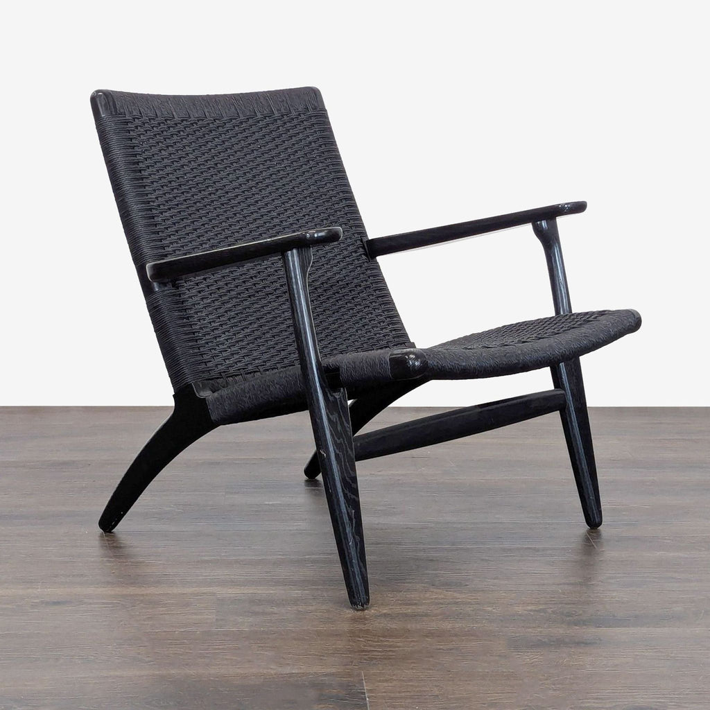 Sleek Carl Hansen & Son lounge chair with a black woven seat, angled wood frame, and wide, comfortable armrests.