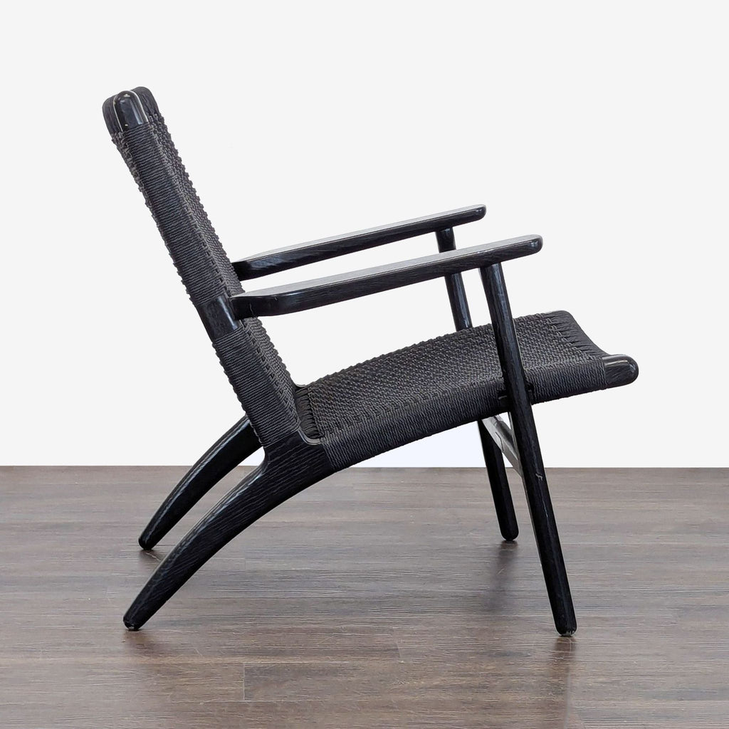 Carl Hansen & Son lounge chair featuring black woven seat and back, sturdy angled wood frame, and minimalist design.