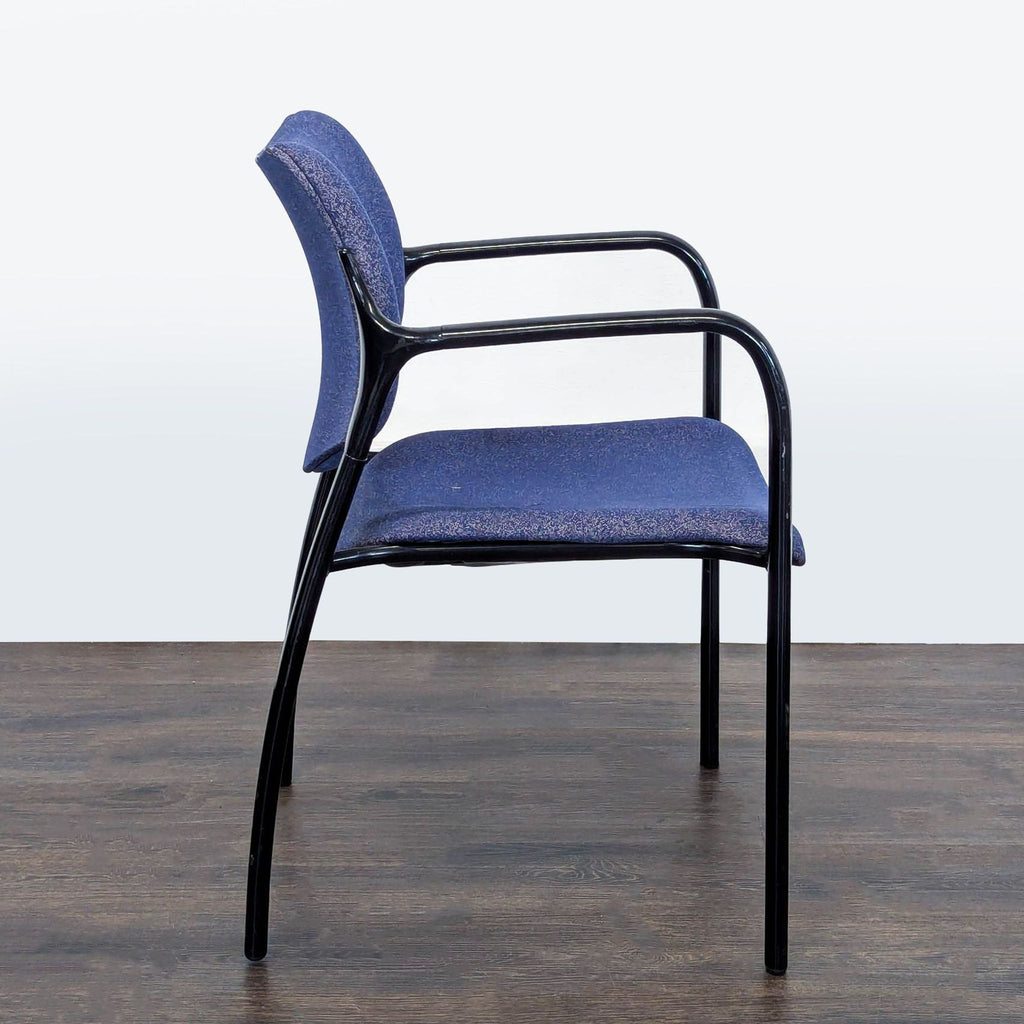 Side profile of a Herman Miller guest chair, highlighting blue cushioned seat, curved backrest, and black metal arms.