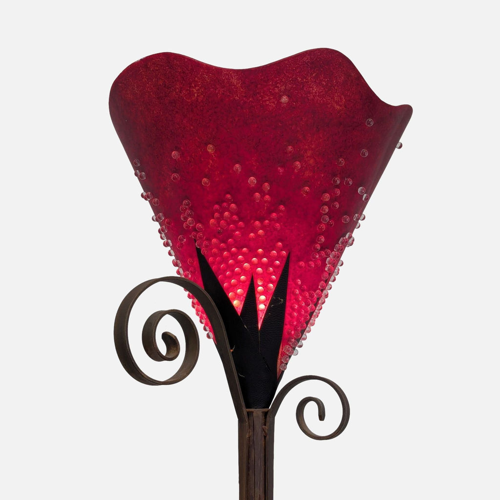 2. Close-up of a vibrant red glass lamp shade with bubble textures and black scrollwork metal accents.  