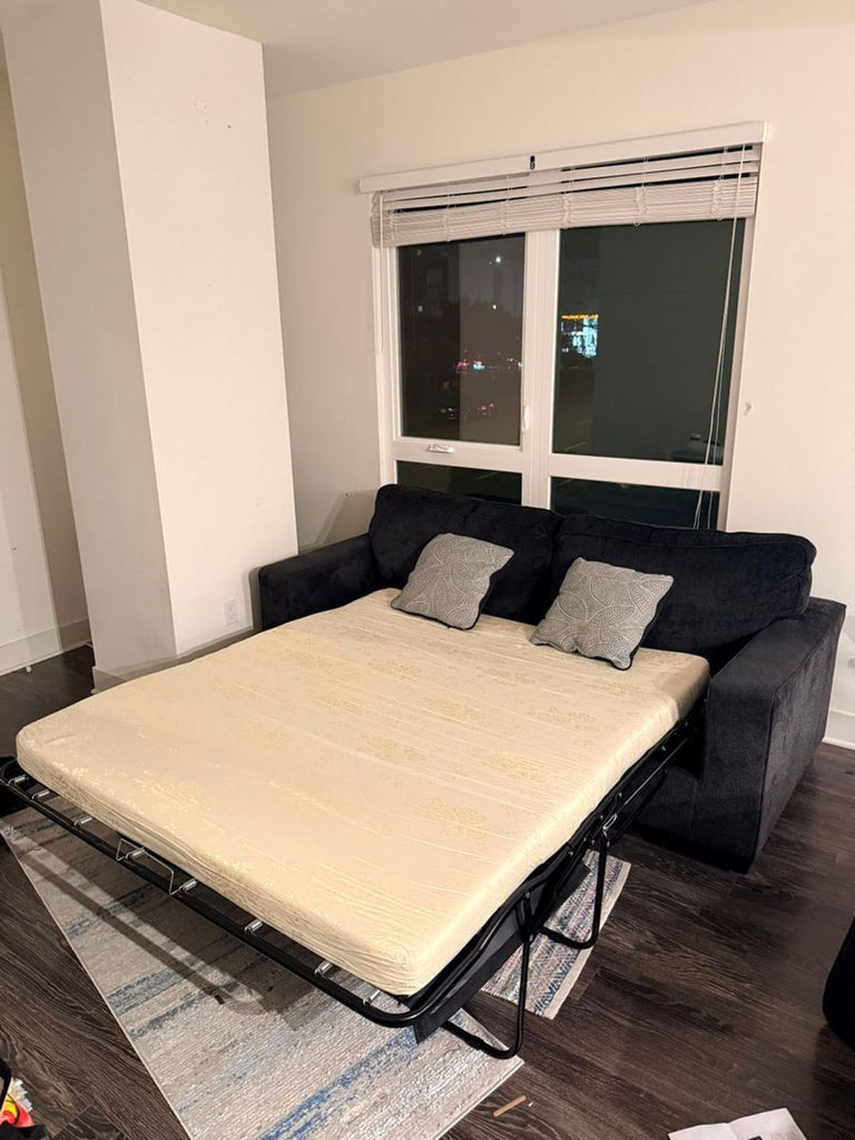 3. Sleeper sofa by Ashley Furniture extended to reveal a pull-out bed frame and mattress in a living room.