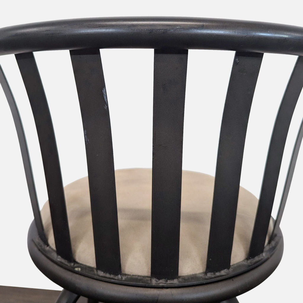 Detail of black metal stool’s curved slatted backrest and beige round seat cushion, highlighting bar design.