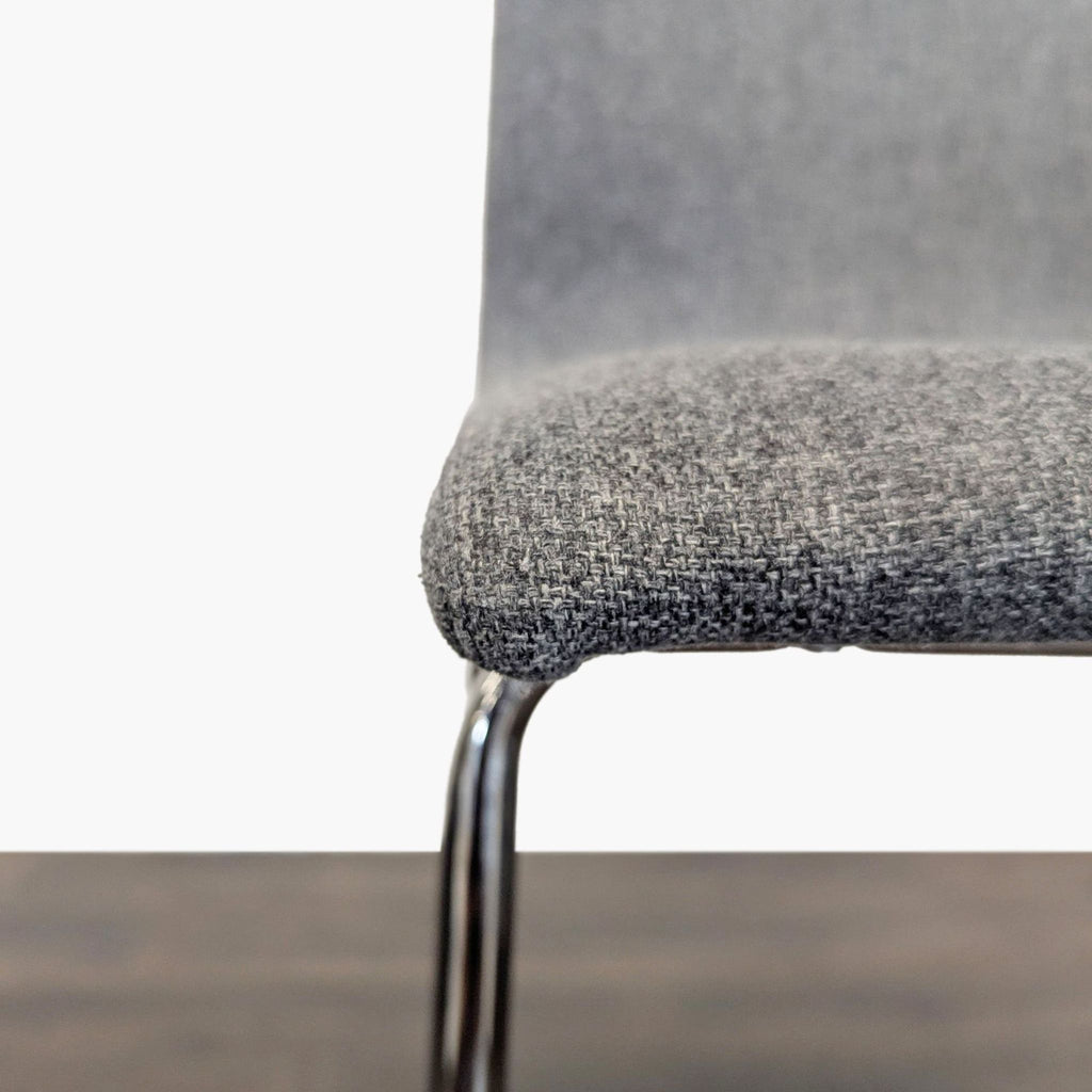 Close-up of the textured grey fabric seat and chrome-finished legs of an Ikea counter stool.