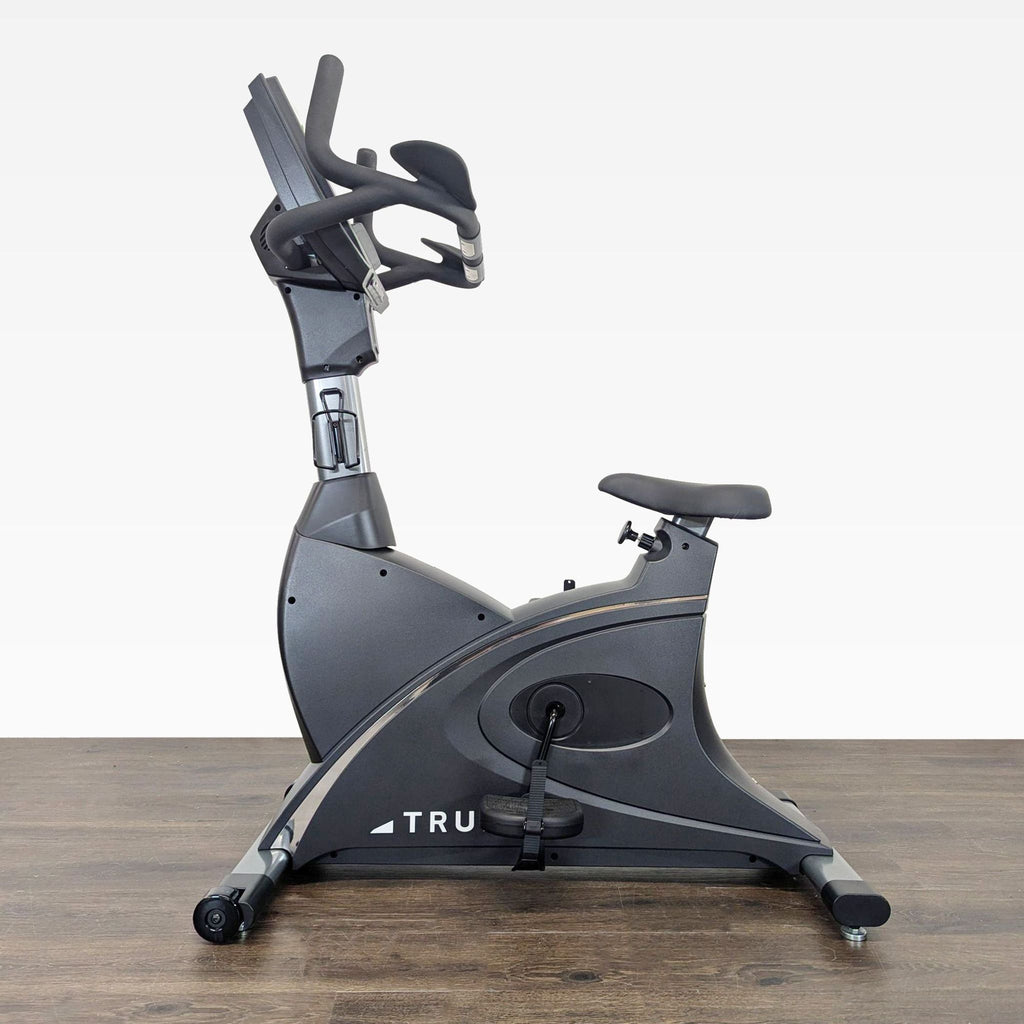 True upright exercise bike with adjustable seat, strap pedals, and handlebar controls for smooth home workouts.