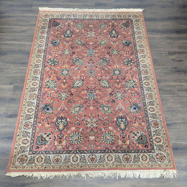 Classic oriental rug with rich background, intricate floral patterns, and beige, navy, and gold border motifs.