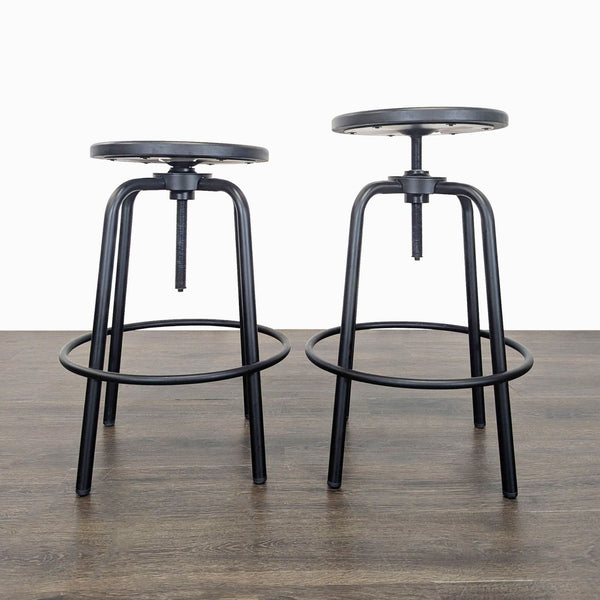 1. Pair of black metal adjustable round stools with circular footrests, shown on a wood floor.