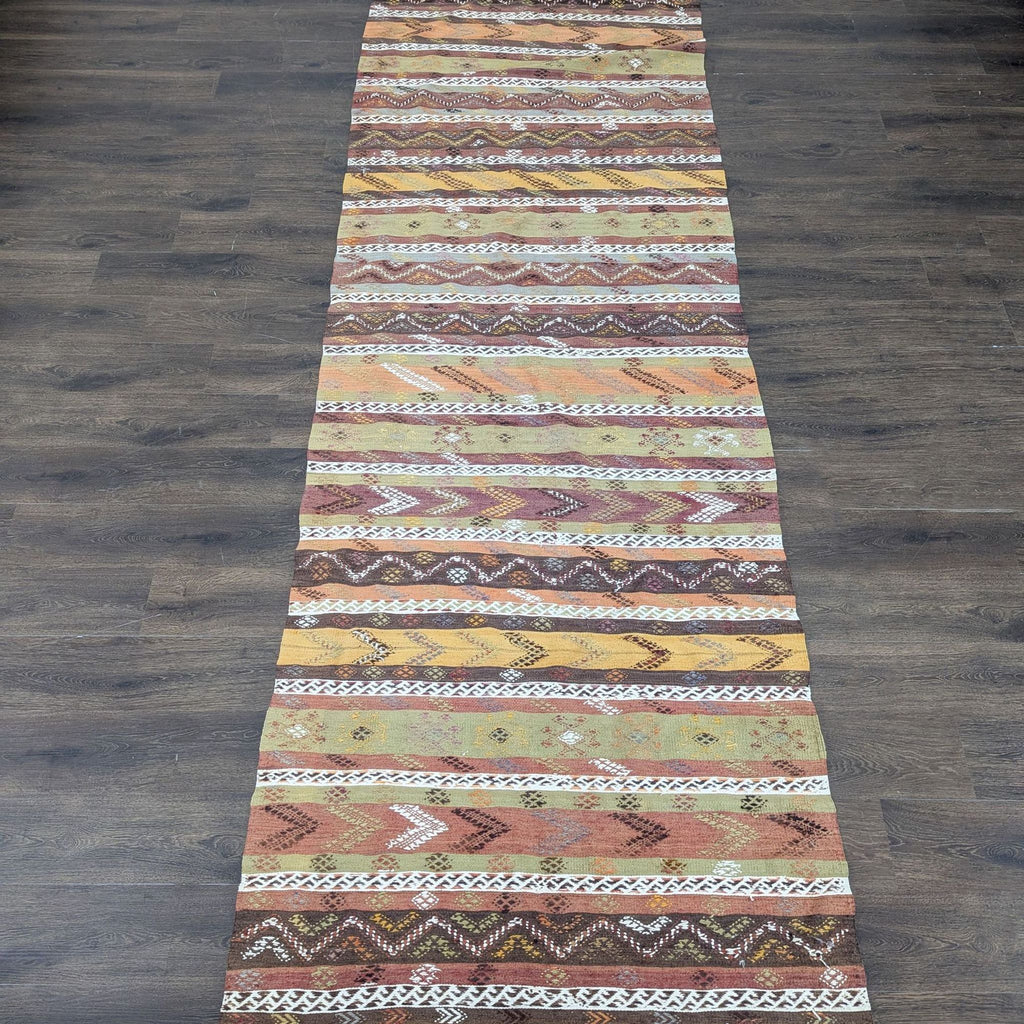 1. Long runner rug with handwoven zigzag and diamond patterns in brown, orange, yellow, and white earth tones.  