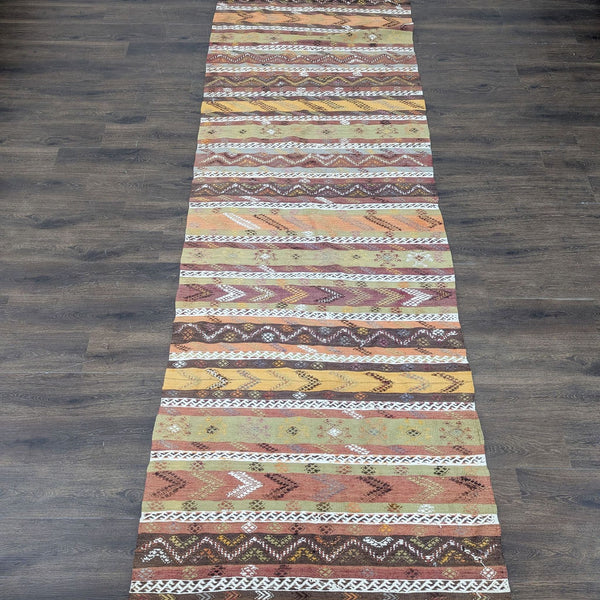 1. Long runner rug with handwoven zigzag and diamond patterns in brown, orange, yellow, and white earth tones.  