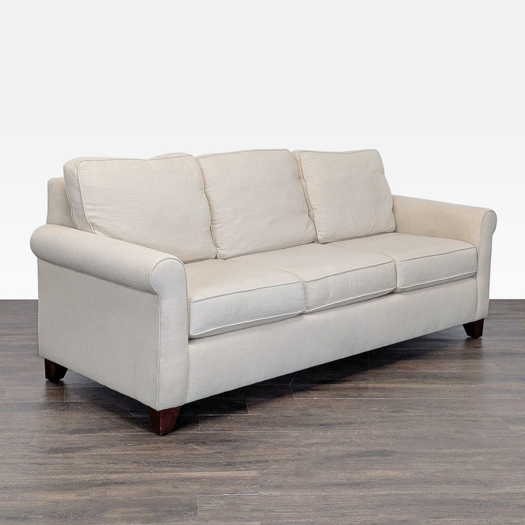Classic Pottery Barn 3-seat beige sofa featuring plush cushions and sturdy wooden legs.