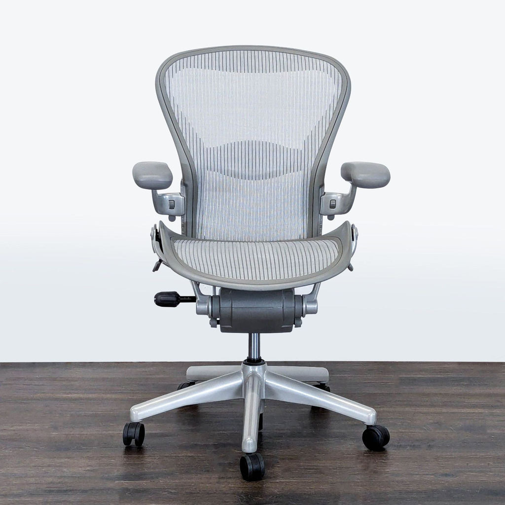 Front view of a Herman Miller Aeron office chair in light gray mesh with adjustable armrests and rolling wheels.