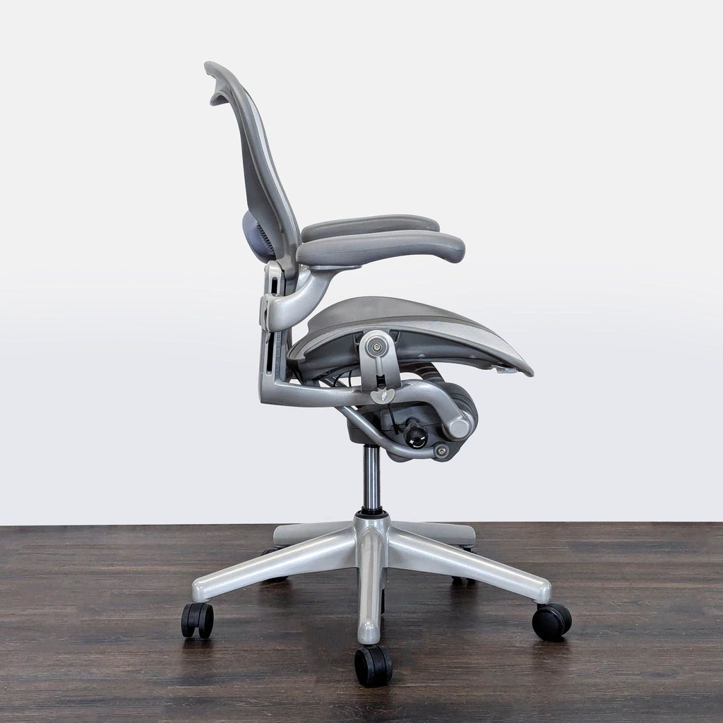 Side profile of a Herman Miller Aeron office chair showing its adjustable armrests, mesh design, and ergonomic support.