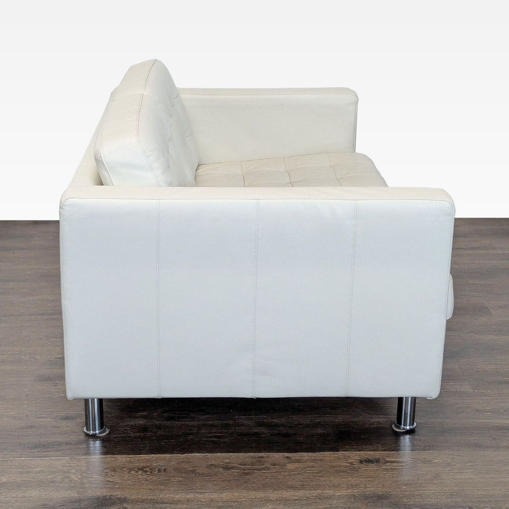 3. Side view of white Ikea loveseat with clean lines, tufted cushions, and sturdy metal legs on a dark floor.
