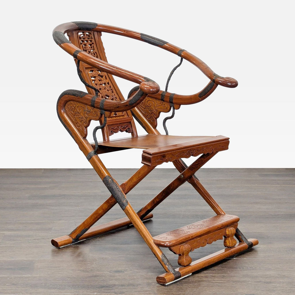 Folding lounge chair in warm wood finish featuring intricate carvings, metal details, and horseshoe-shaped back.