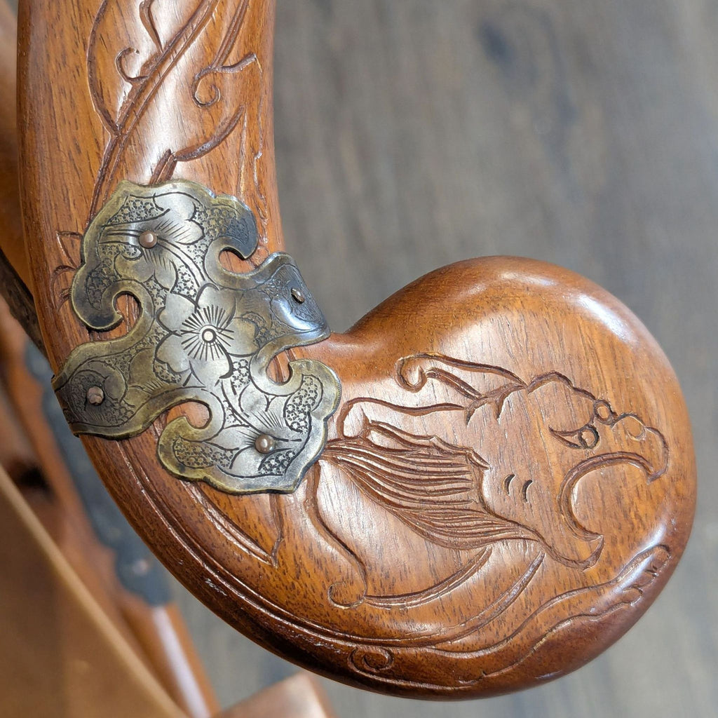 Decorative wooden lounge chair with sculpted horseshoe back, ornate carvings, and metal hardware; both functional and stylish.