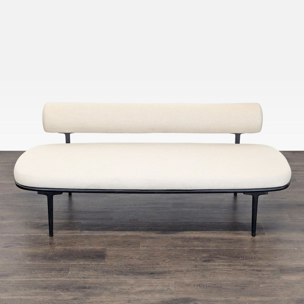 Minimalist CB2 couch with cream upholstery and thin black metal legs, perfect for stylish homes or offices.