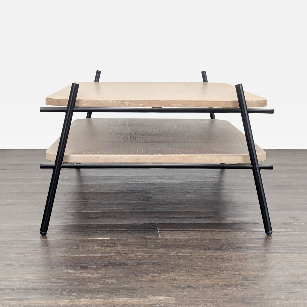 2. Side view of a rectangular coffee table, showing two light wood tiers supported by angled black metal legs.