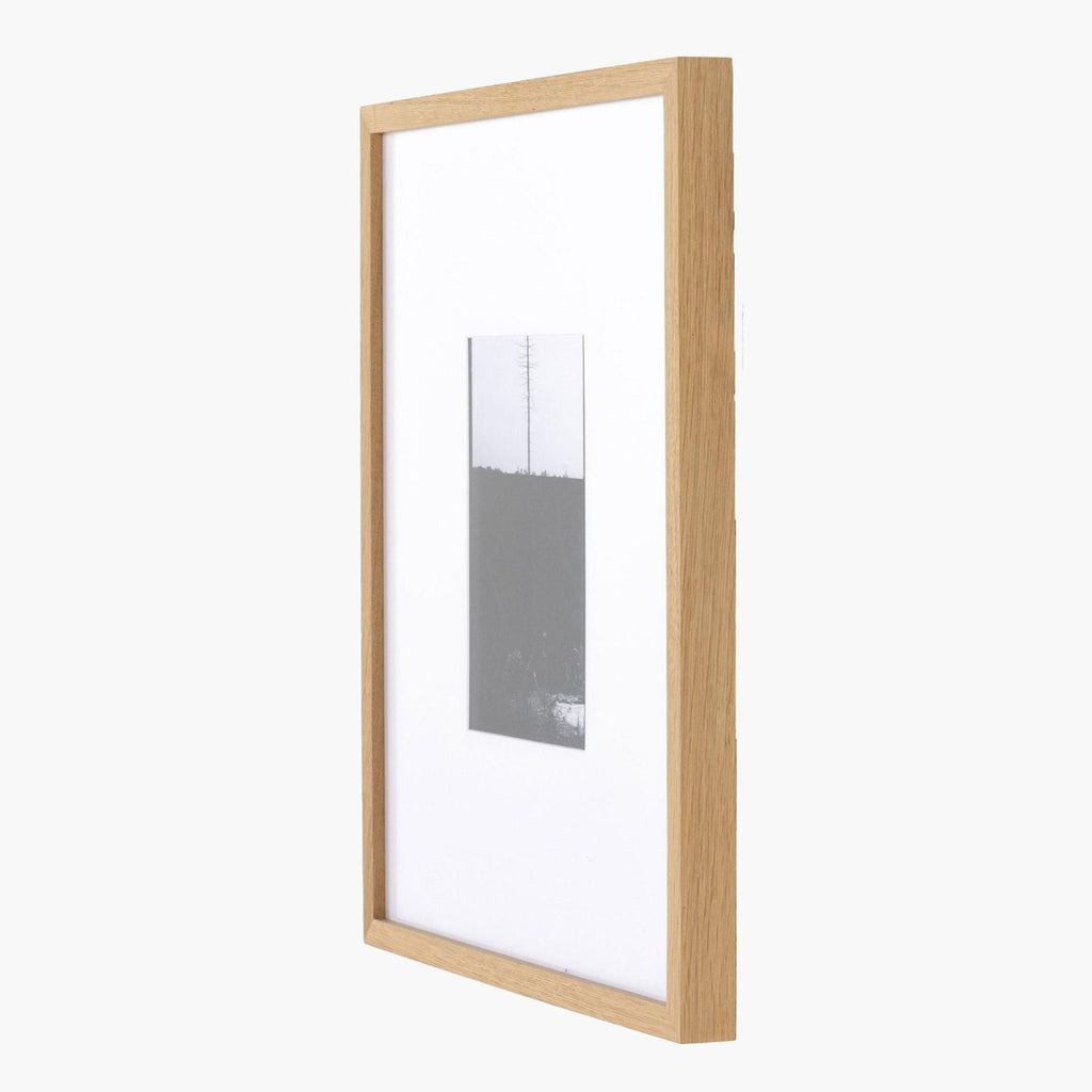 3. Side angle of a framed black and white lone tree print, emphasizing its slim, minimalist wood frame design.