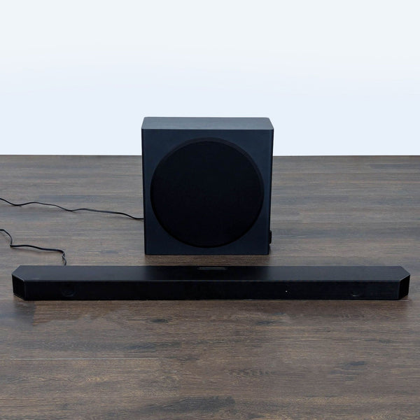 Samsung soundbar and wireless subwoofer set on a wooden floor, ideal for enhancing home audio experiences.