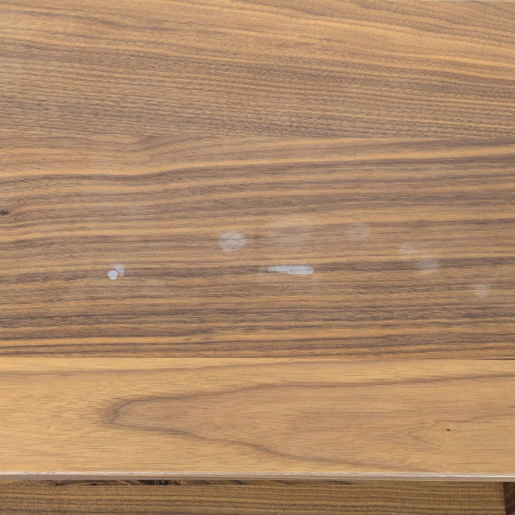 3. Detail view of the walnut finish on the Room & Board bookshelf top, with visible marks and natural wood grain.