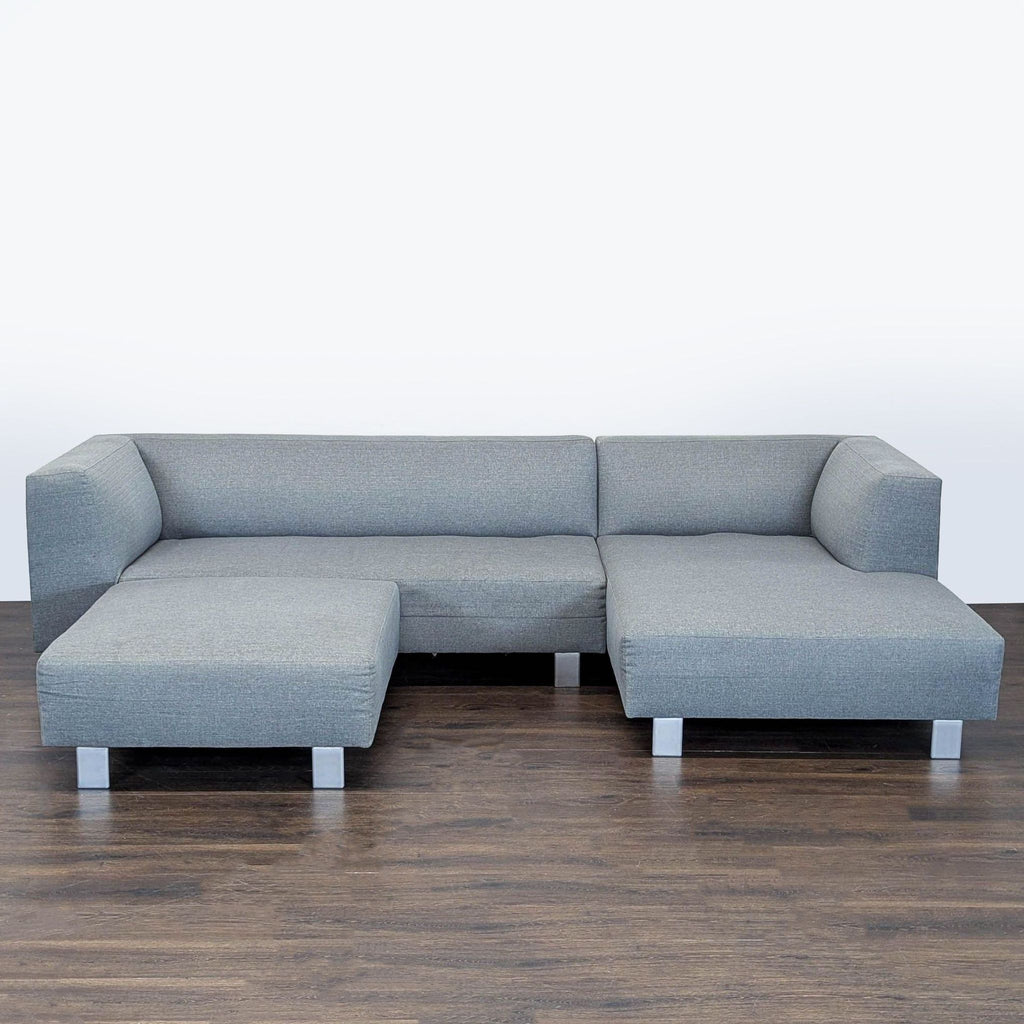 1. Gray Room and Board sectional sofa with ottoman and metal legs, featuring modern low-profile arms on hardwood floor.