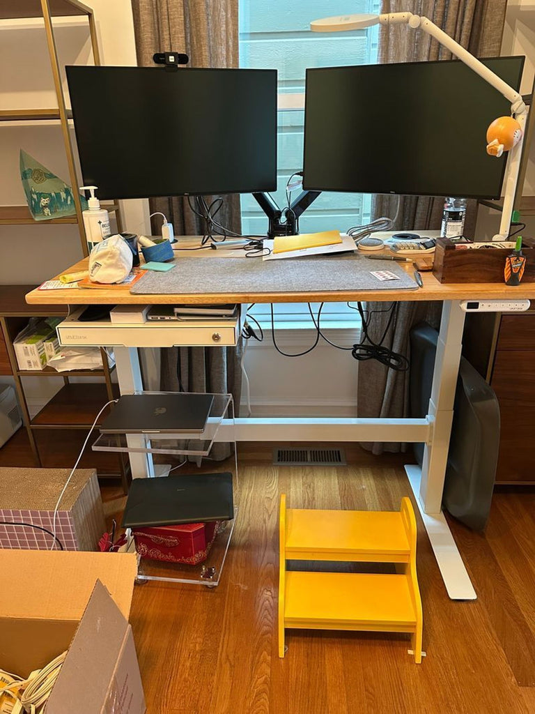 1. Uplift sit-stand desk setup with dual monitors, lamp, and office accessories in a home office environment.