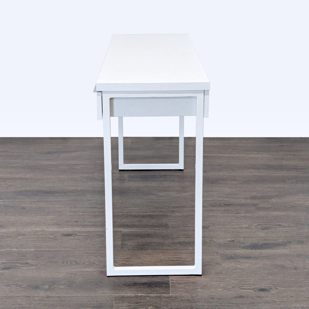 3. Side view of a sleek white IKEA desk with metal legs and a simple, contemporary look for any décor.