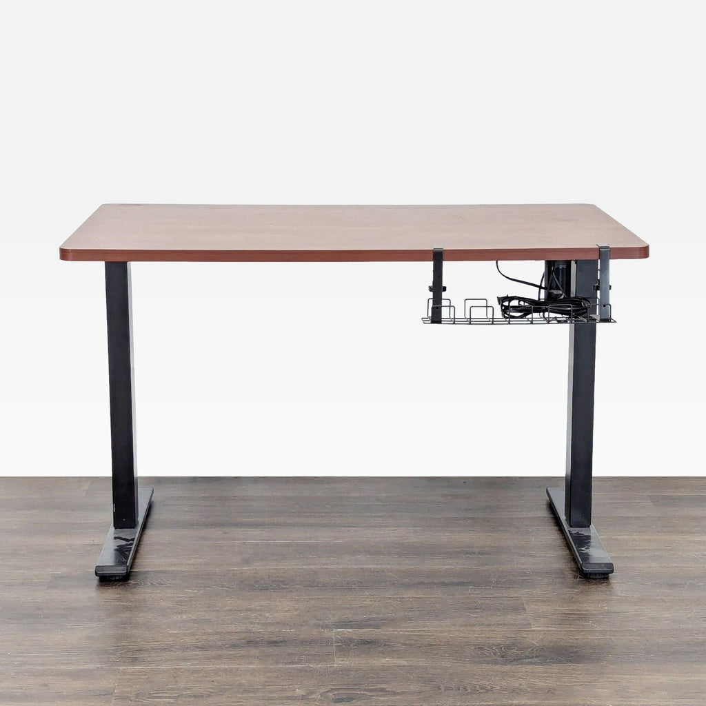 Sturdy Flexispot sit-stand desk with black legs, a wood surface, electric adjustment, and under-desk cable tray.