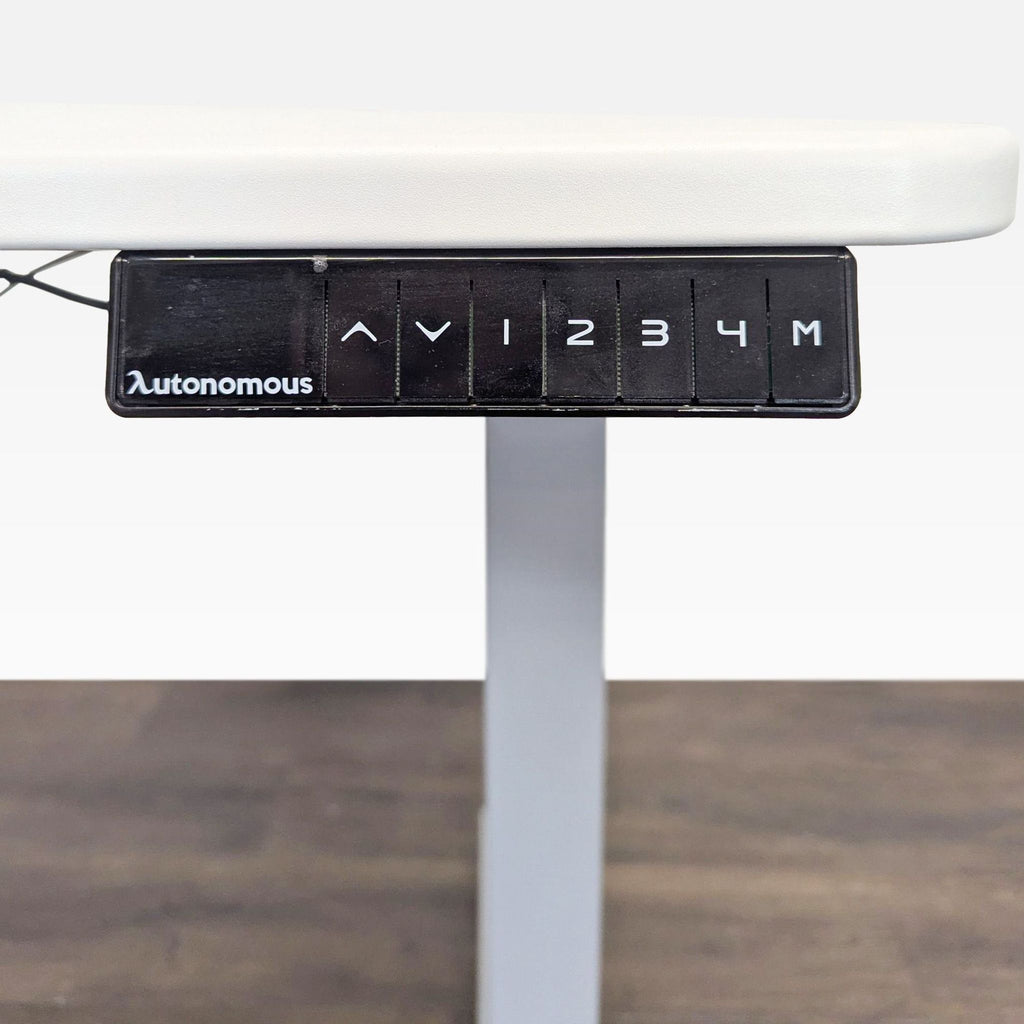 Modern white desk by Autonomous with metal frame, spacious surface, and four memory settings for height preferences.