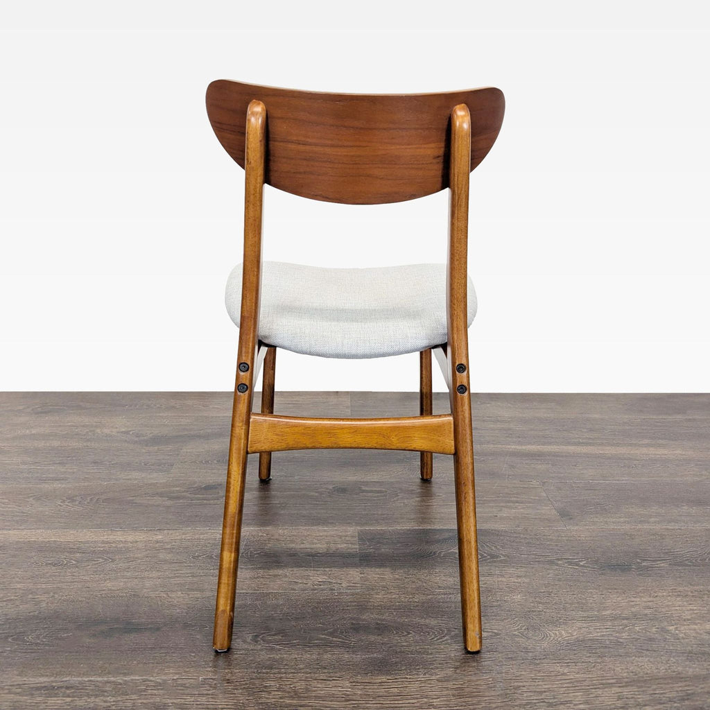 2. Rear view of a single West Elm dining chair showing wood frame, curved backrest, and cushioned seat.