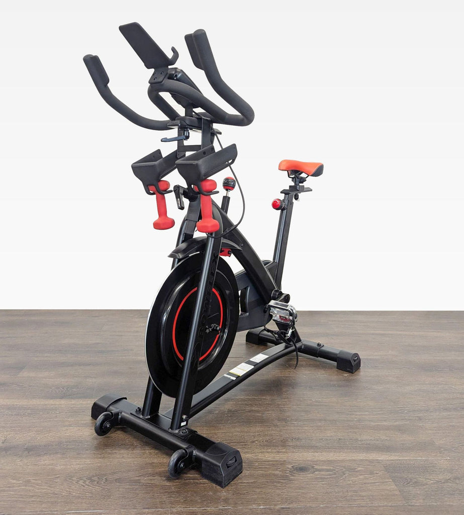 Angled front view of Bowflex C6 exercise bike, showing handlebars, included dumbbells, and sturdy build.  