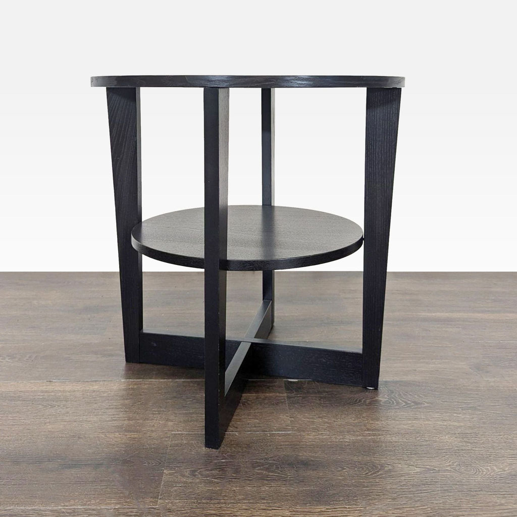 2. Side view of a modern black end table with circular shelf and angled legs, set on wood flooring.